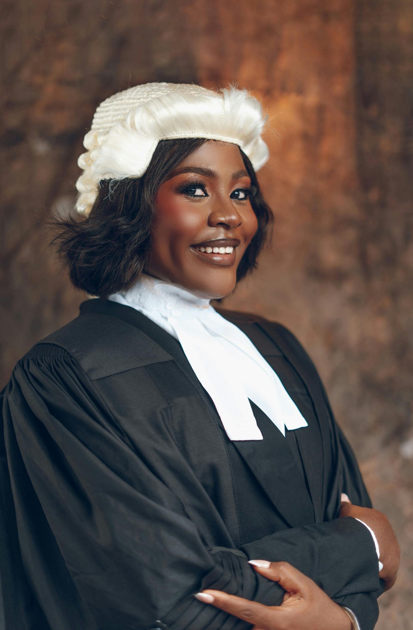Smiling female lawyer in traditional legal attire posing confidently indoors.
